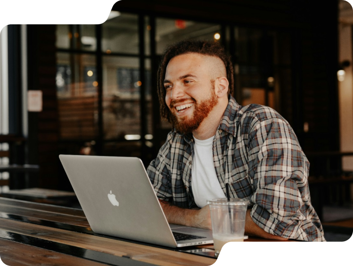 Man smiling at table on laptop.