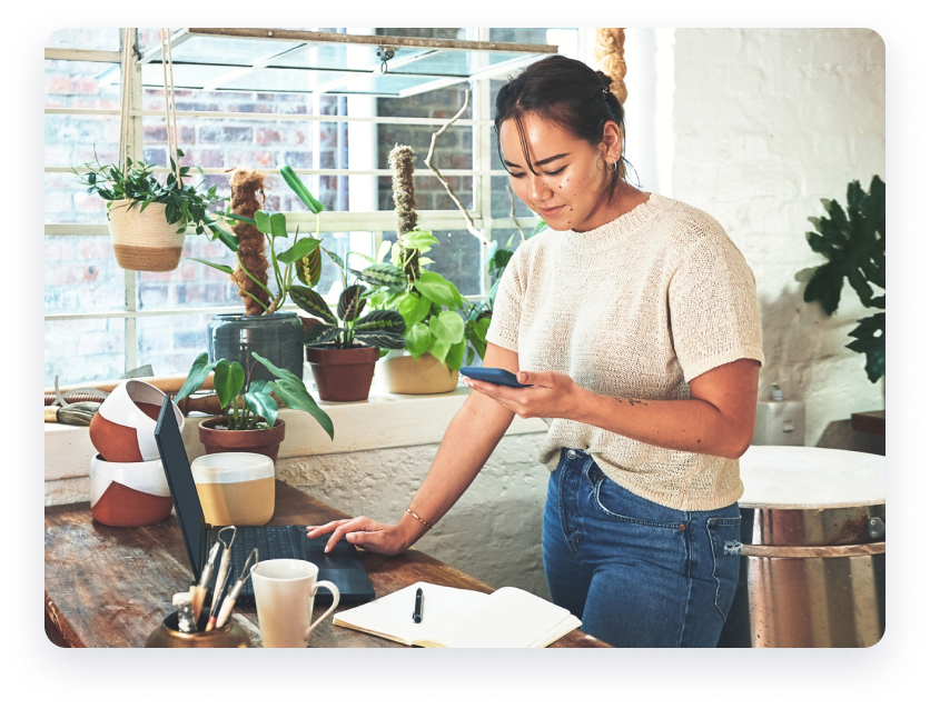 Woman on laptop with plants surrounding her.