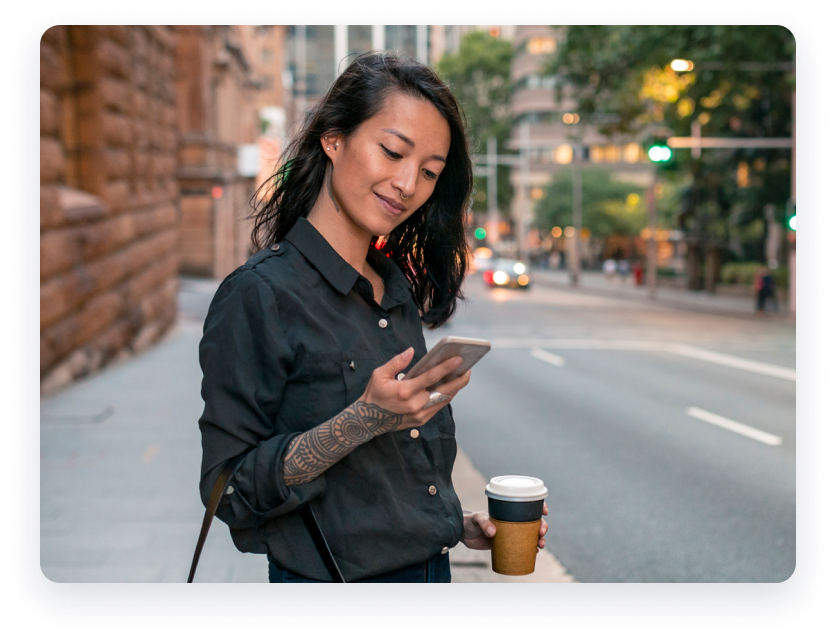 Woman on the street holding phone and coffee