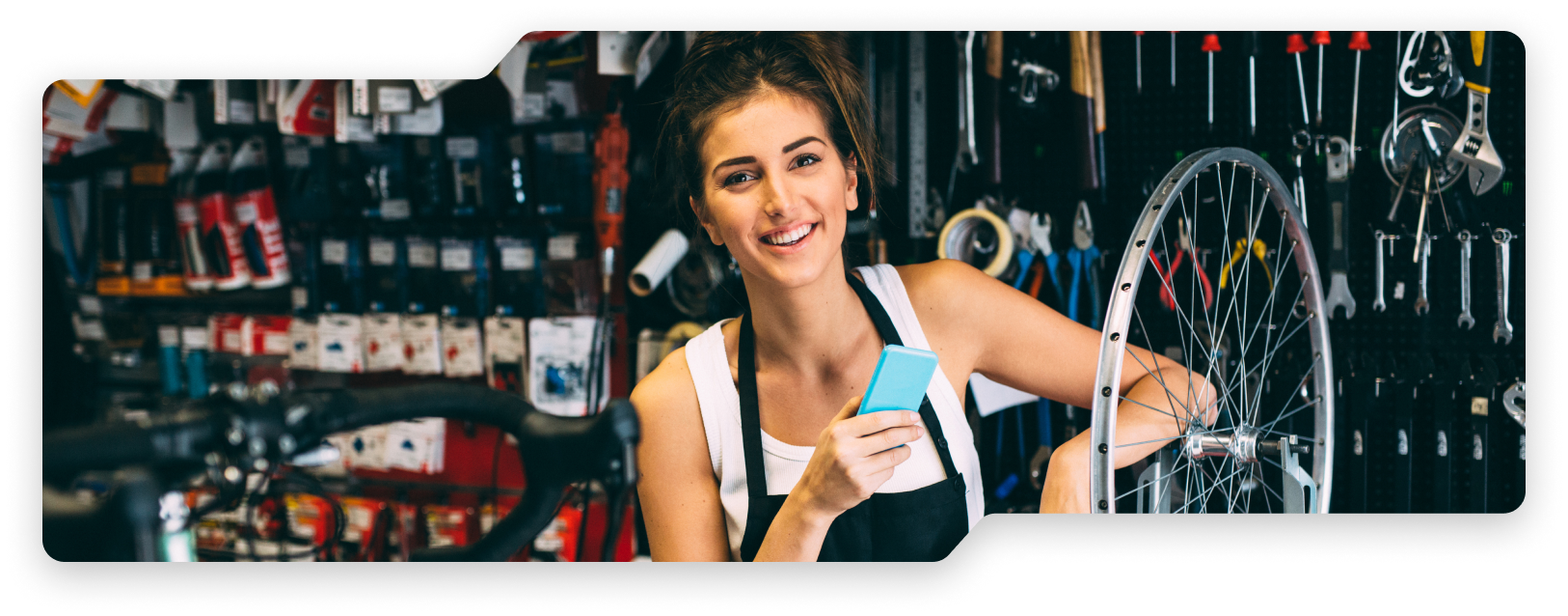Woman holding phone at a bike shop.
