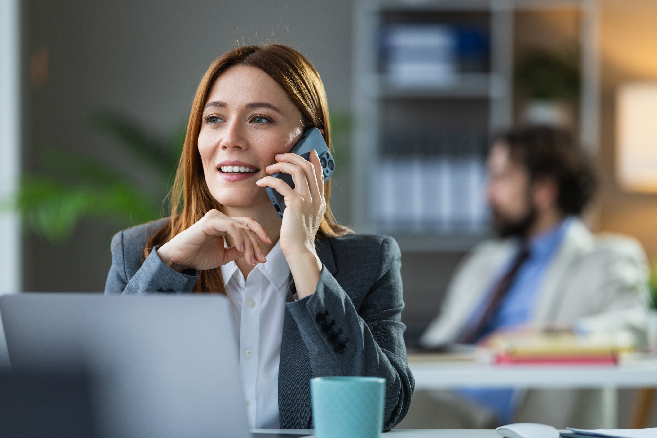 Businesswoman answering a call on her phone through single number reach at her office desk